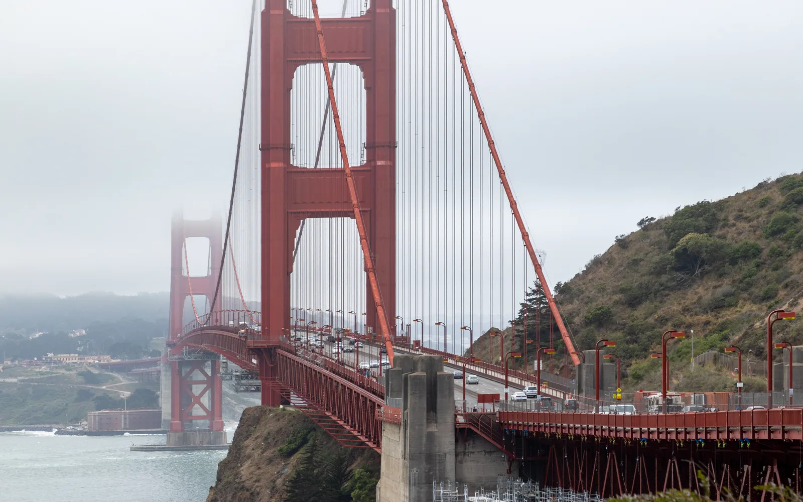 The Golden Gate Bridge spanning the strait between San Francisco and Marin County, viewed from the Vista Point with fog and the Pacific beyond.